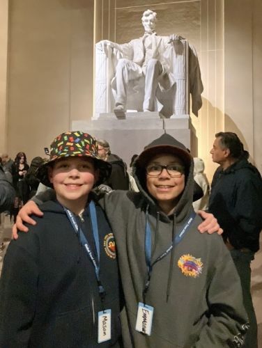 Emmanuel from Columbia Falls, M, stands with his arm around his good friend in front of the towering white statue of Abraham Lincoln inside the Lincoln Memorial in Washington, D.C.