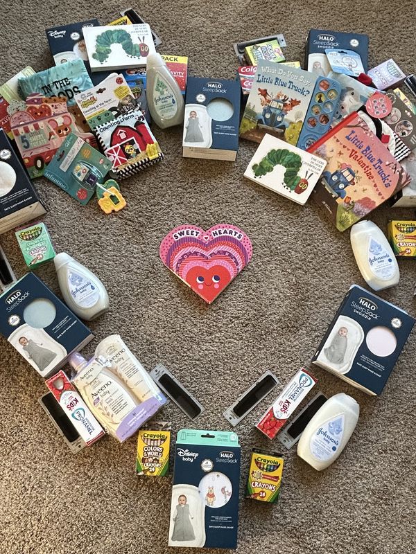 A heart-shaped display of baby sleep sacks, books, and toys for Scott County Foster Care