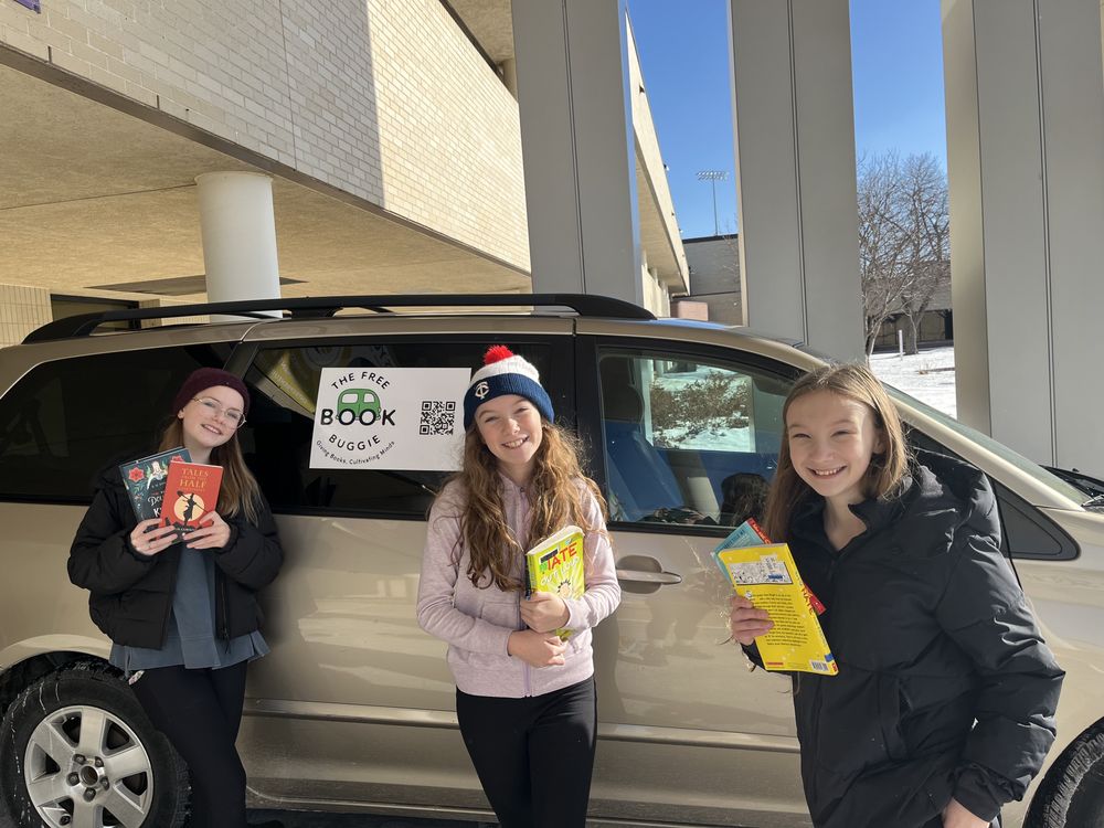 Elsie, Greta, and Lucy with The Free Book Buggie, sorting donated books for their community