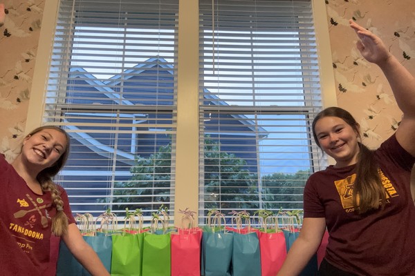 Carys and Aubrey holding up the decorated gift bags they made for their teachers