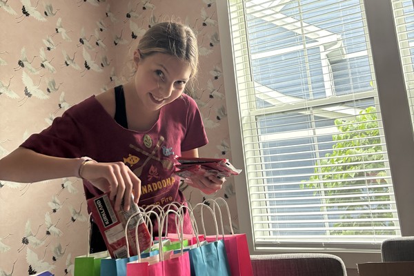 A student filling the teacher gift bags with snacks and supplies