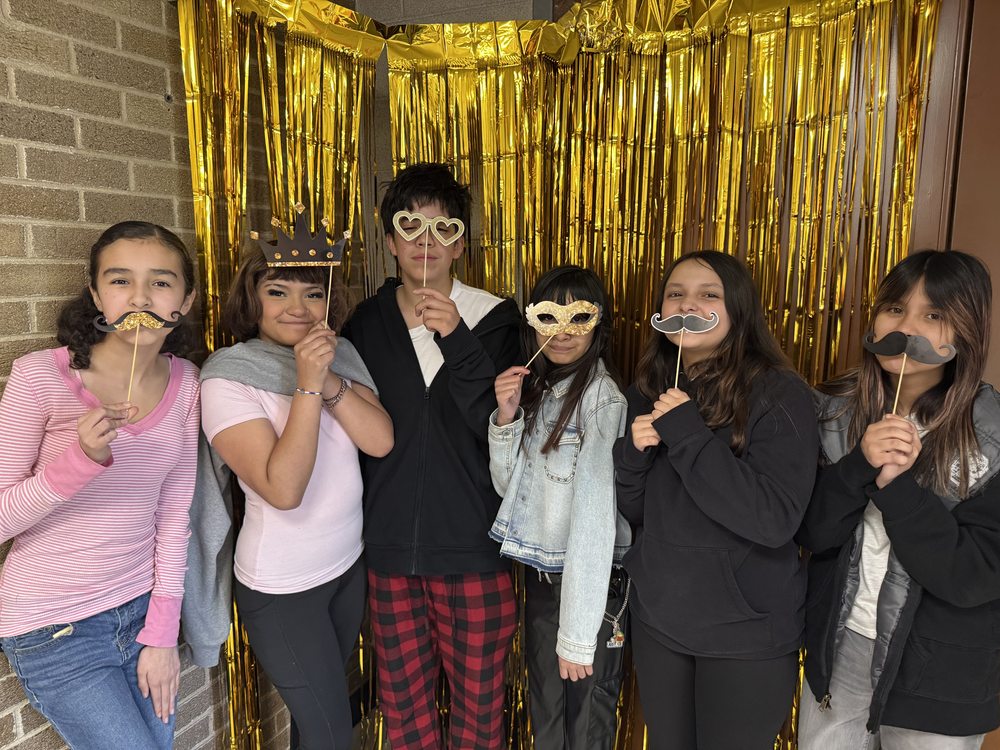 Cameron and classmates posing with mustache props at the student council photo booth fundraiser