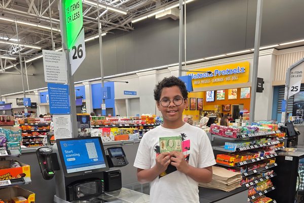 A student holding up a Benjamin Project $100 card at the checkout while gathering supplies